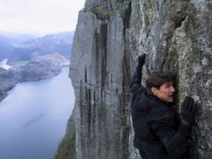 Tom Cruise em uma cena do filme que cai dos penhasco (Reprodução)
