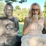 Fazendo carão com um drink na mão ao lado de uma estátua de Buda, Madonna critica Trump